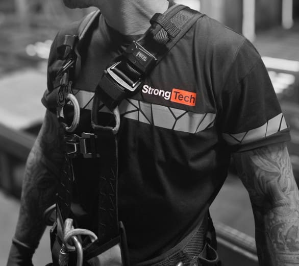 StrongTech-medewerker met valbeveiliging in een StrongTech-shirt