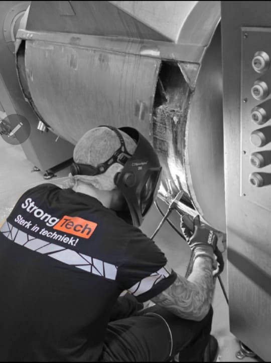 StrongTech-monteur aan het lassen aan een industriële machine